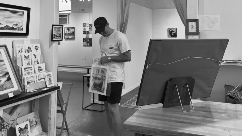 Boyfriend standing in art studio in Asheville, holding a painting