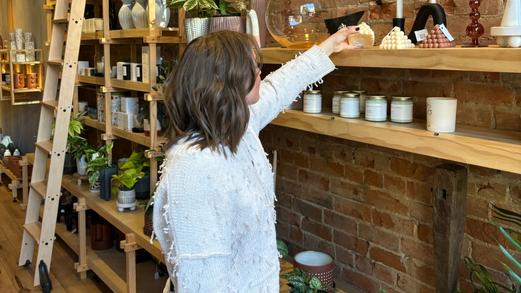 Emily reaching for a candle on a shelf at a flower shop in Cincinnati, Ohio