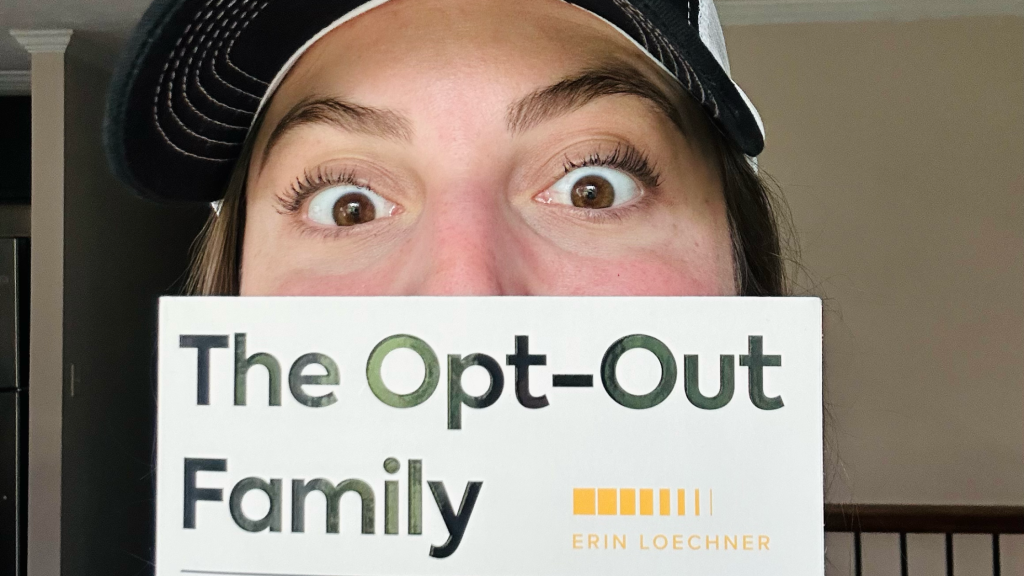 Emily holding The Opt-Out Family book over her mouth up by her eyes.